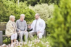 Physician sits on bench with patients
